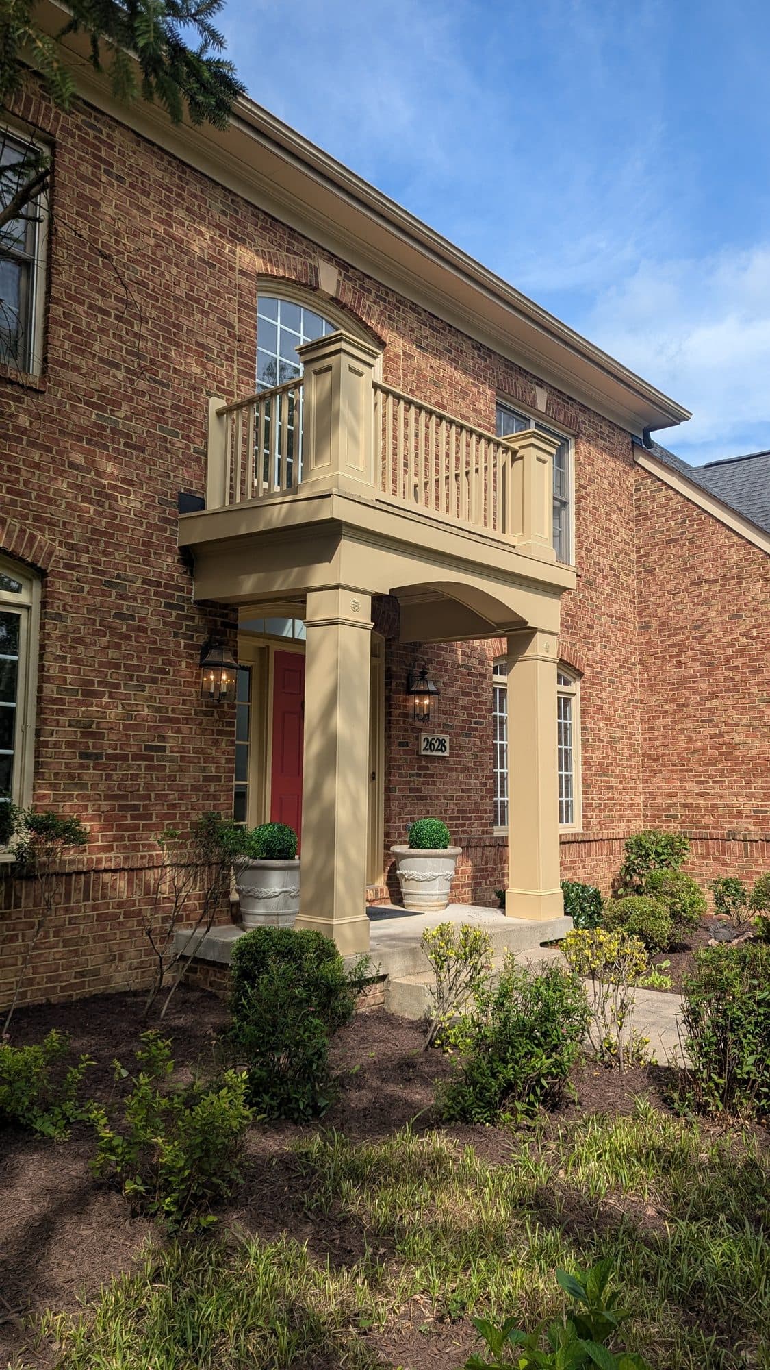 Brick home exterior with a covered front porch and balcony after a flat roof repair